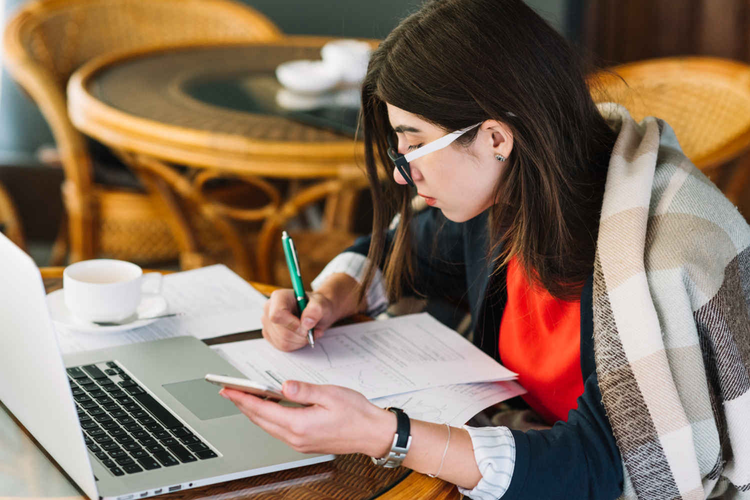 A woman at a table with a laptop and pen, focused on her work for CAT Degree College Admissions.