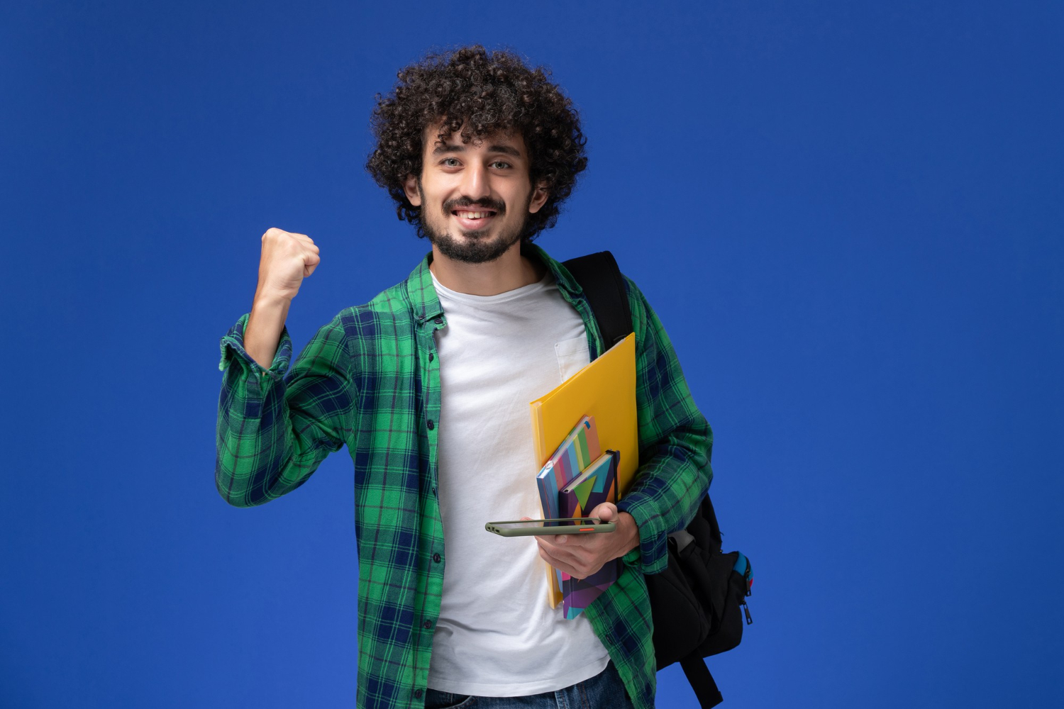A man with curly hair and a backpack raises his fist while holding a folder at BCom degree college Nampally.
