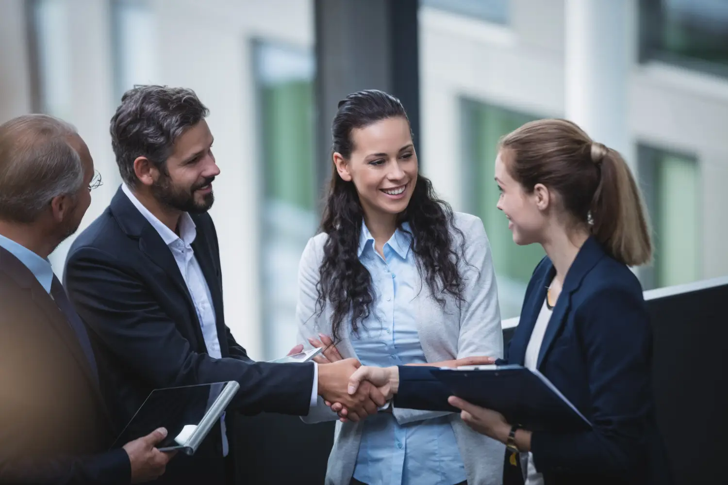 Business professionals shaking hands in an office, symbolizing partnership and collaboration in Industry Connections.