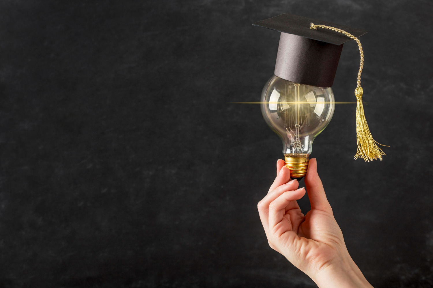 A hand with a graduation cap and light bulb, illustrating the connection between learning and inspiration.